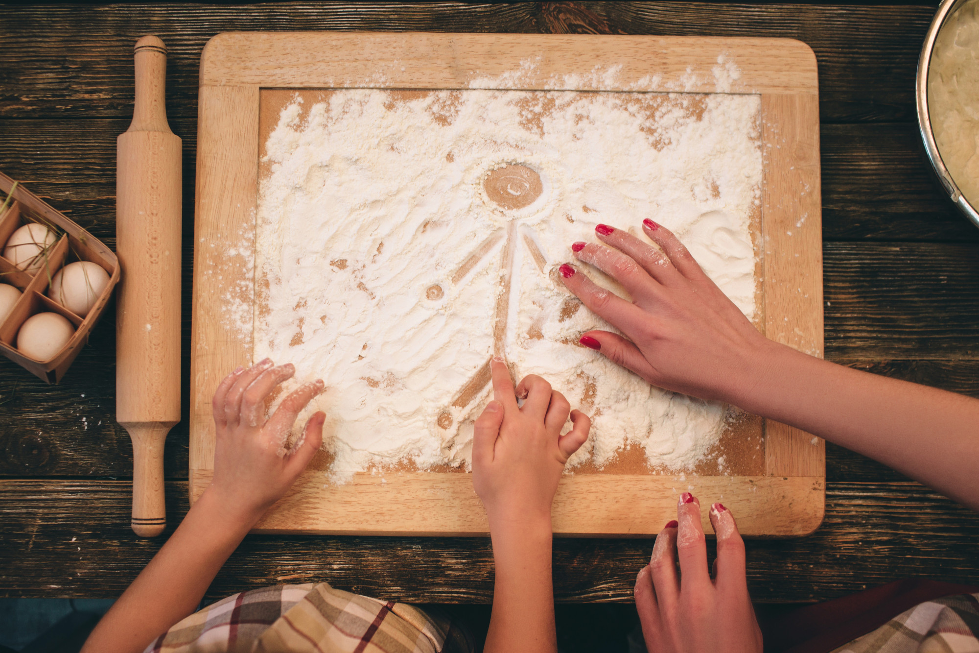 Hands forming dough on wooden board
