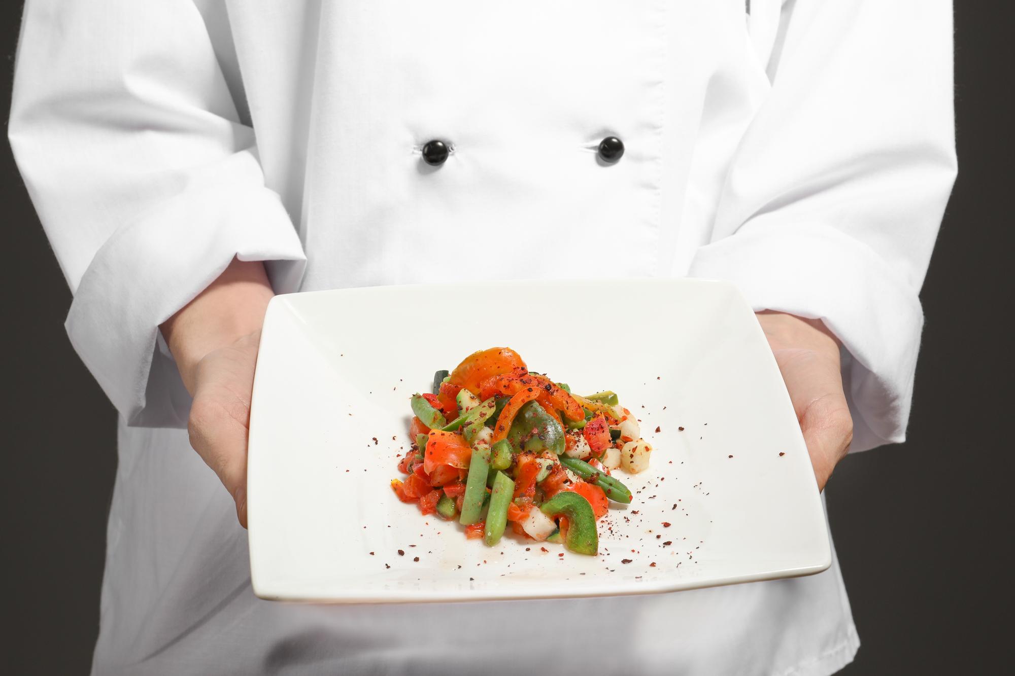 Chef preparing a plated dish in a minimal kitchen